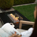 planika rio table outdoor gas fireplace lifestyle people reading book next to fireplace view